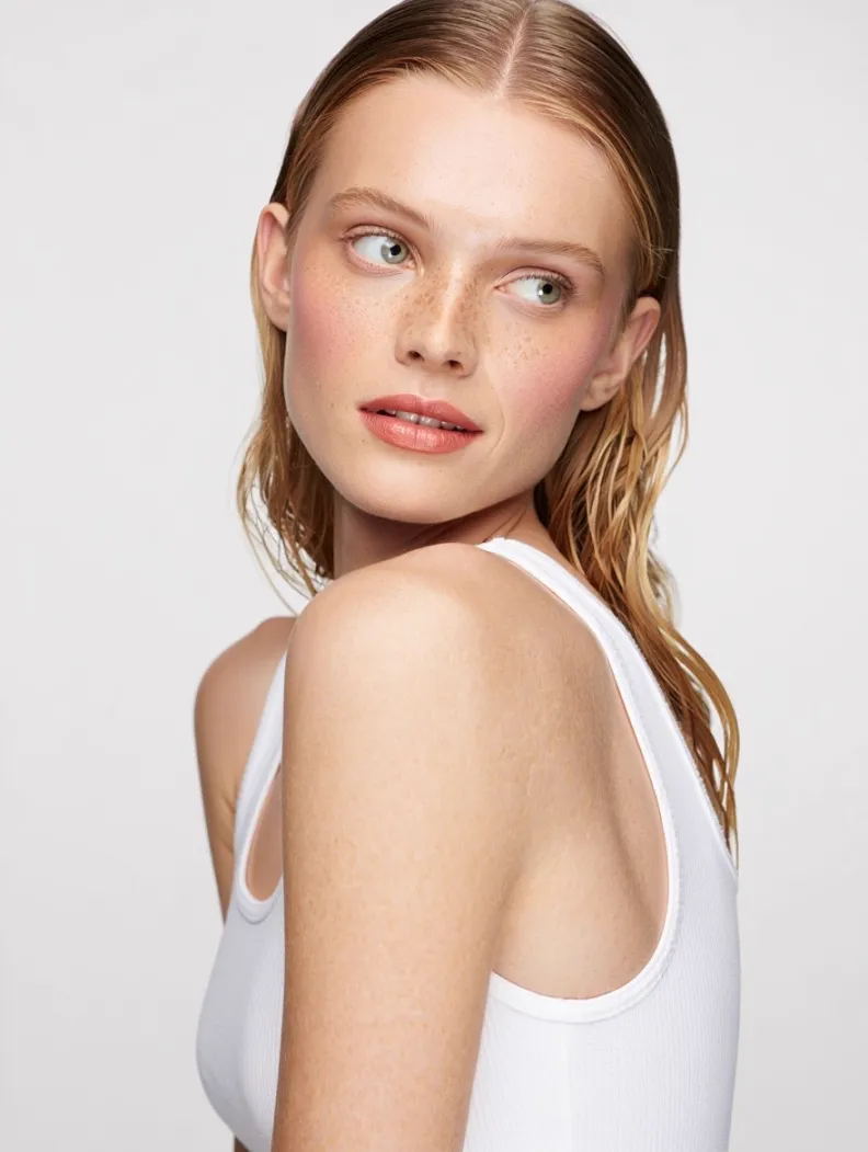 Input — face reference of model with freckles and red-blonde hair, used to lock model identity across MODA AI catalog outputs