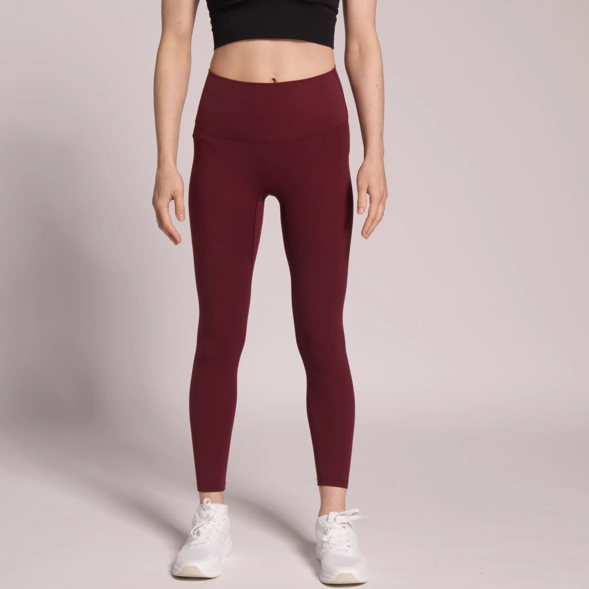 Input — maroon high-waist activewear leggings worn waist-down on neutral studio background, used as garment source