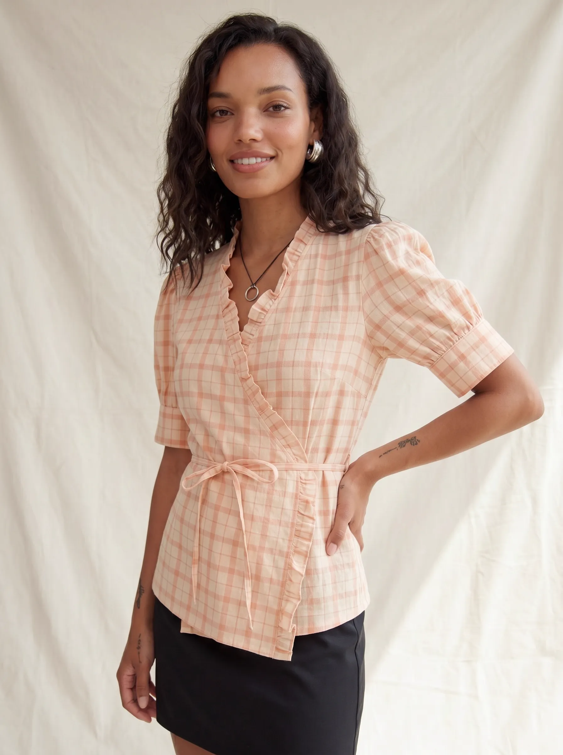 MODA AI output 2 — full-body studio model wearing peach plaid wrap top with belt and ruffle detail