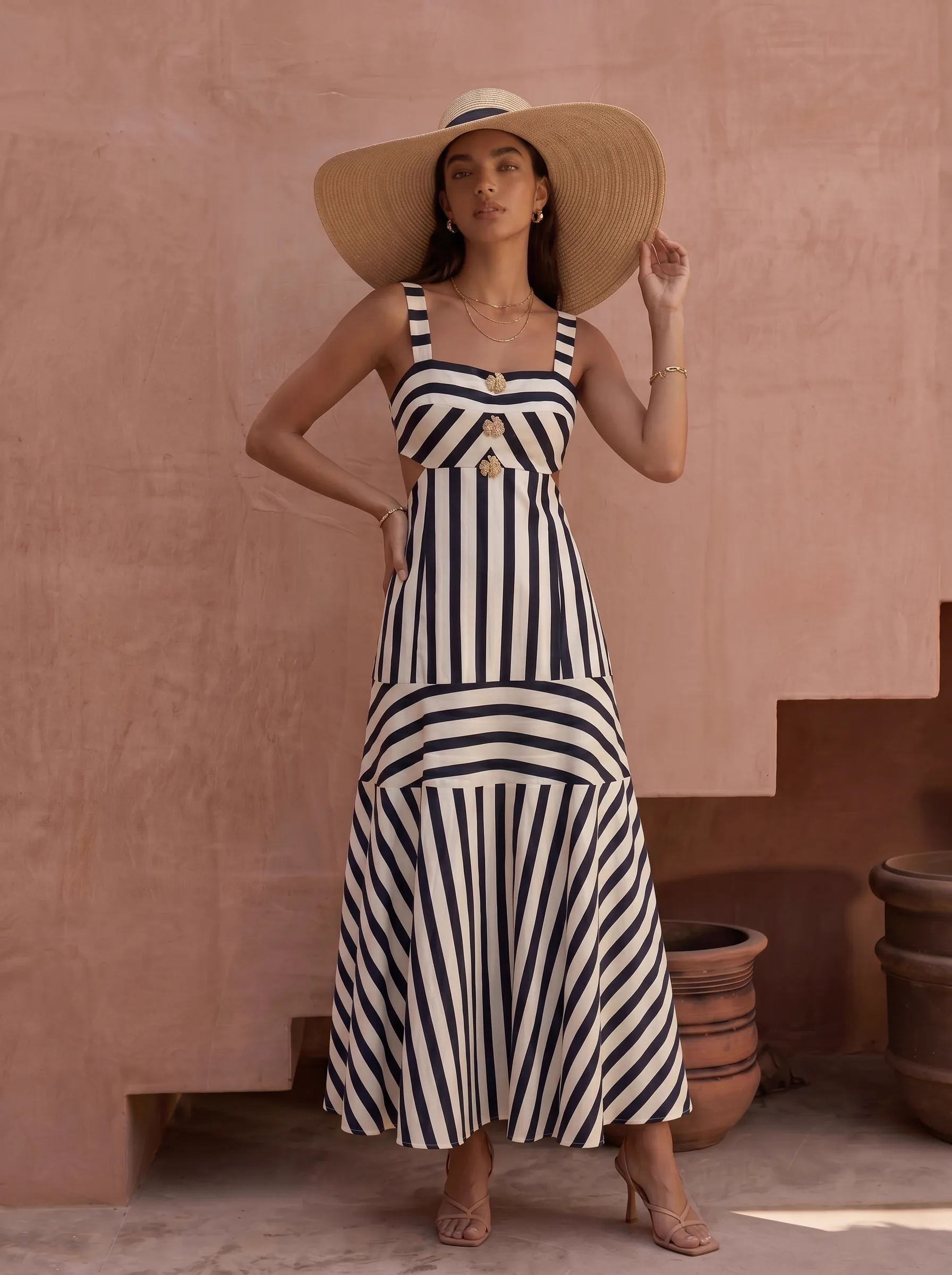 MODA AI resortwear output — navy and cream striped maxi dress with straw sun hat against pink Marrakech wall, demonstrating the navy stripe colorway